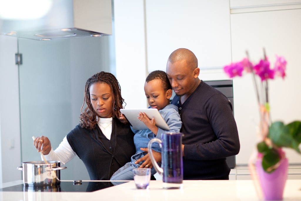 Family in kitchen looking at a tablet